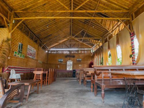 un ristorante vuoto con tavoli e sedie in legno di Glamping Orak Arik a Karangmanggu