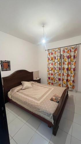 a bedroom with a bed and a window with a curtain at السعيدية in Saidia 