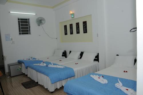 two beds in a white room with blue sheets at Bien Khoi Mini Hotel in Hue