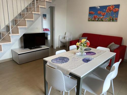 a living room with a dining room table with white chairs at Le Casine di Cervia in Cervia