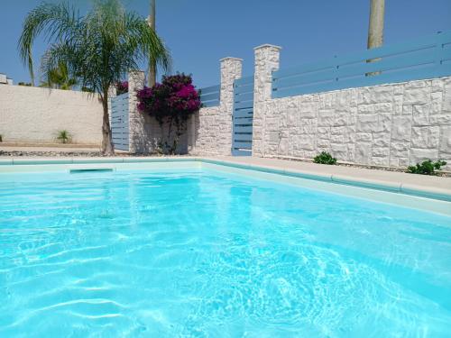 a swimming pool with blue water in front of a wall at Villa Colapesce in Marzamemi