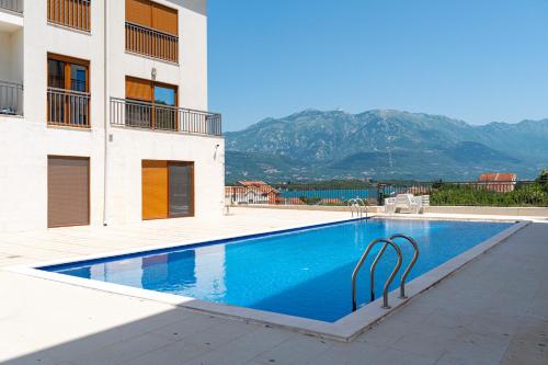 a swimming pool in front of a building with mountains at Apartments Dream in Tivat