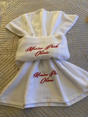 a white towel with red writing on it on a bed at Marina Park OLIWIA in Sveti Vlas