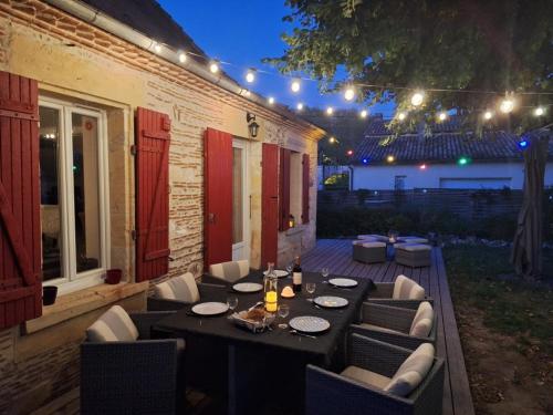 - une table à manger et des chaises sur la terrasse la nuit dans l'établissement Maison au bord de l'eau, à Saint-Avit-Saint-Nazaire