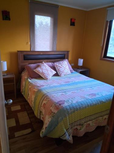 a bedroom with a bed with pillows and a window at Cabaña Tranquila in Villarrica