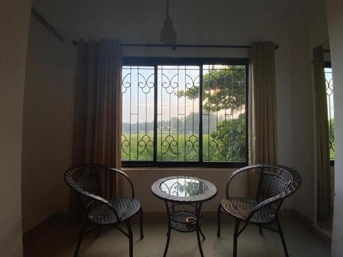 two chairs and a table in front of a window at GreenfieldView in Candolim