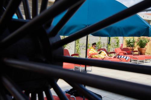 a woman is sitting in chairs under an umbrella at Moagem Industrial Lodge in Viana do Alentejo