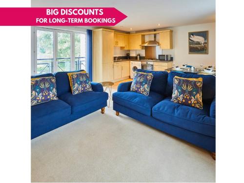 a living room with two blue couches and a kitchen at Modern Comfort 2BR Flat with Free Parking in Oadby in Oadby