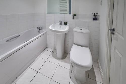 a white bathroom with a toilet and a sink at Modern Comfort 2BR Flat with Free Parking in Oadby in Oadby