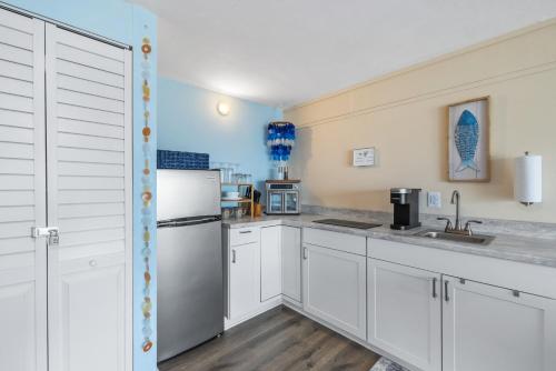a kitchen with white cabinets and a refrigerator at Coastal Retreat 213 at Cedar Cove Condos in Cedar Key