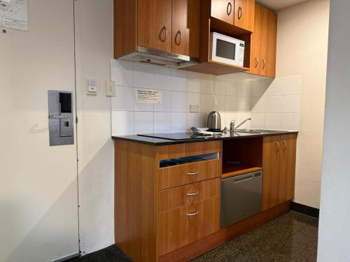 a kitchen with wooden cabinets and a sink and a microwave at Stylish City Stay in Parramatta Pool , Parking in Sydney