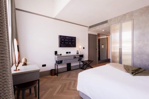 a bedroom with a bed and a desk and a sink at Hart Shoreditch Hotel London, Curio Collection by Hilton in London