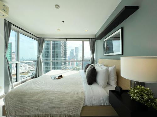 une chambre avec un grand lit avec une grande fenêtre dans l'établissement Stylish 2BR City View - BTS St.Louis - Ultra Fast Wifi, à Bangkok