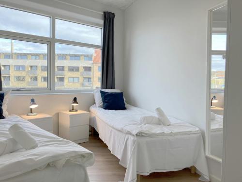 two beds in a room with a large window at Central and Spacious Apartment for 10 in Randers