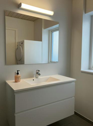 a bathroom with a white sink and a mirror at Spacious Apartment for 7 in Sabro