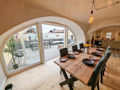 a dining room with a wooden table and a large window at The Old Bakery at Sobechleby in Blšany