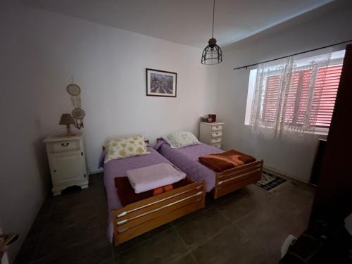 a bedroom with a bed with purple sheets and a window at The Viewpoint House - Njeguši in Njeguši