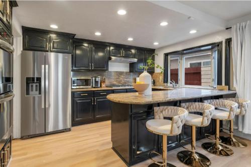a kitchen with black cabinets and a large island with bar stools at Designer Dream- Pool and spa- Game Room- Sleeps 10 in Los Angeles
