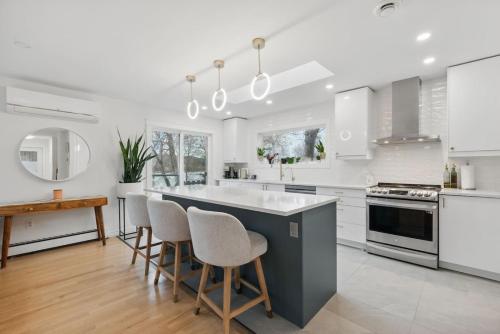 a kitchen with white cabinets and a island with bar chairs at The Tranquil lake-house at Fletchers Lake in Fall River