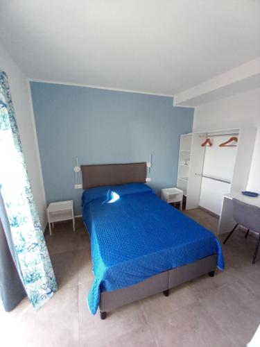 a bedroom with a blue bed with a blue bedspread at Holidays Cefalù Rooms in Cefalù