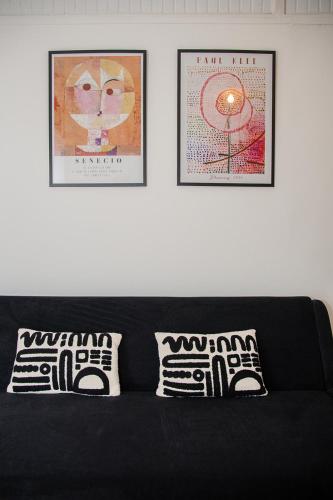a black couch with two pillows and two pictures at Habitation PLUM in Pointe-à-Pitre