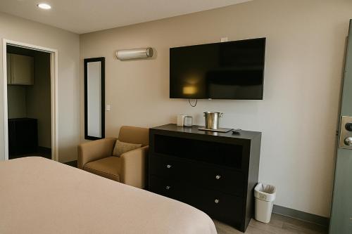a bedroom with a bed and a dresser with a television at Rodeway Inn El Cajon - San Diego East in El Cajon