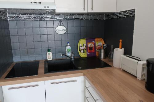 - une cuisine avec un évier et un mur en carrelage noir dans l'établissement Studio Valras vue Port et Mer Wi-Fi gratuit, à Valras-Plage