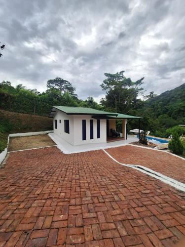 a small white house with a brick driveway at CASA BLANCA EN LA VEGA in La Vega