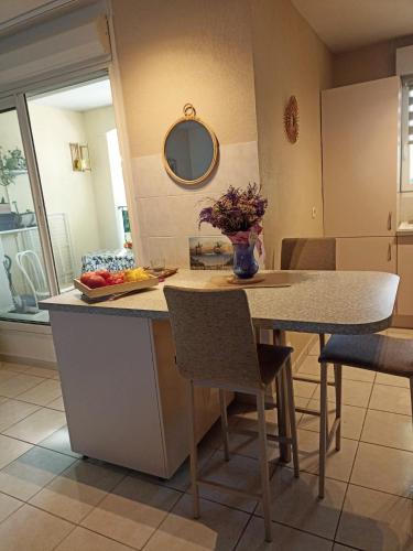 Una cocina con una mesa con un jarrón de flores encima. en Mauguio-Carnon P2 60 m2, tout confort, spacieux, climatisé, wifi, balcon, parking privé couvert, 15 min de la mer, de Montpellier, en Mauguio