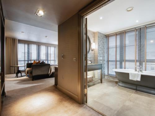 a bathroom with a tub and a living room at Dakota Glasgow in Glasgow