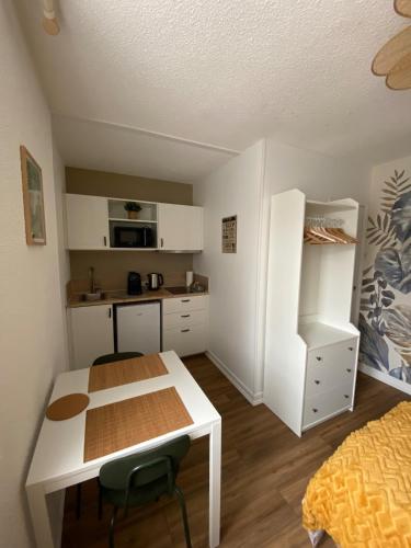 Elle comprend une petite cuisine avec une table blanche et un réfrigérateur blanc. dans l'établissement Agréable Studio Caen Venoix, à Caen