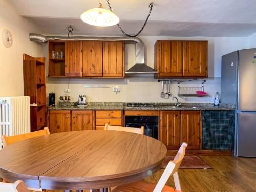 a kitchen with a wooden table and a refrigerator at La Sosta nel Borgo in Pettorano sul Gizio