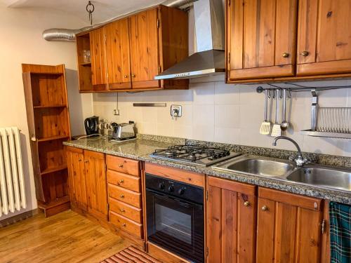 a kitchen with wooden cabinets and a stove and a sink at La Sosta nel Borgo in Pettorano sul Gizio