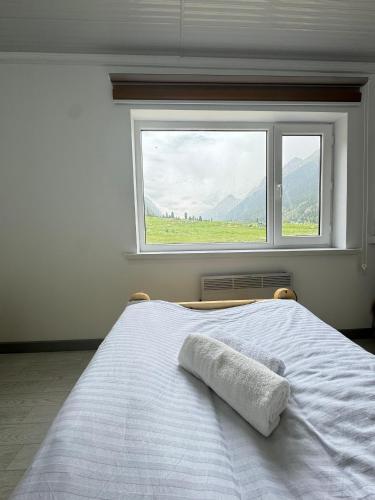 a bedroom with a white bed with a window at Altygat Lodge Barskoon in Barskoon