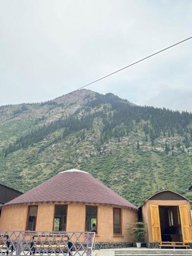 a house with a mountain in the background at Altygat Lodge Barskoon in Barskoon