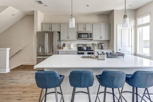 a kitchen with a large white island with blue chairs at 3 Bedroom 4 Bathroom House Tampa Sleeps 10 Private Garage Near Stadium in Tampa