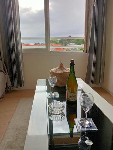 - une bouteille de vin assise sur une table en verre avec deux verres dans l'établissement TRES BEL APPARTEMENT Ploumanac'h Centre, à Perros-Guirec