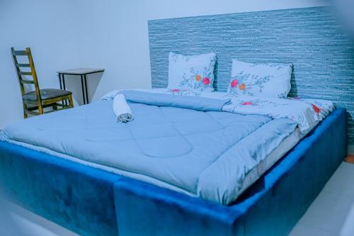 a large bed with blue sheets and pillows at Blue Moon Apartment in Ruhengeri