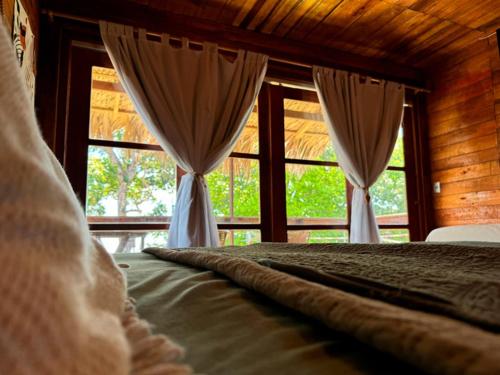 a bedroom with a bed with curtains and windows at Pousada AldeiA Cotijuba in Belém