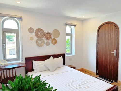 a bedroom with a bed and a table and two windows at Anriva Hoi An in Hoi An