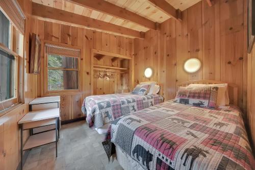 two beds in a room with wooden walls at Kit Carson Lodge in Kit Carson