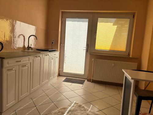 a kitchen with white cabinets and a door with windows at Ihr Kuschelnest in Wathlingen