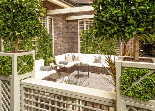 a patio with white furniture and potted plants at Dakota Glasgow in Glasgow