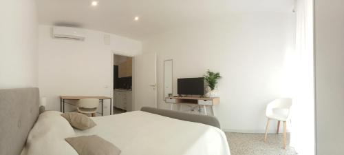 Un dormitorio blanco con una cama y un televisor. en Cinghiale Bianco, en Cagliari
