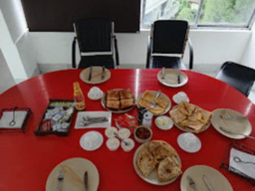 a red table with plates of food on it at BLUE ANGEL Guest House in Shillong