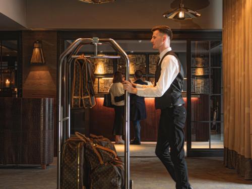 a man in a suit standing next to a suitcase at Dakota Glasgow in Glasgow