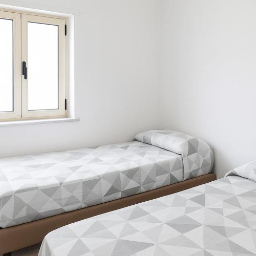 two beds in a room with a window at Appartamenti ABR Corso in Le Castella