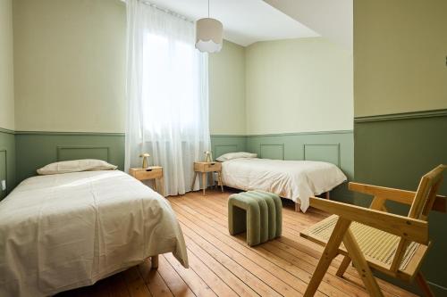 Cette chambre comprend 2 lits dans une chambre dotée de murs verts et de parquet. dans l'établissement L Ecrin des Minimes, au Mans