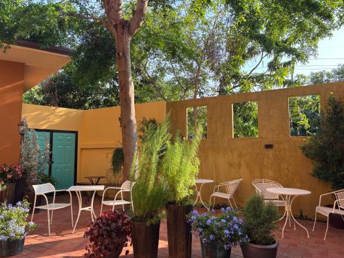 a patio with tables and chairs and a tree at Kireeya Villa in Phetchaburi