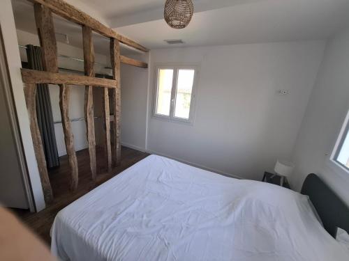 a bedroom with a white bed and a window at Gîte du Petit Guilhem in Montaut-les-Crénaux